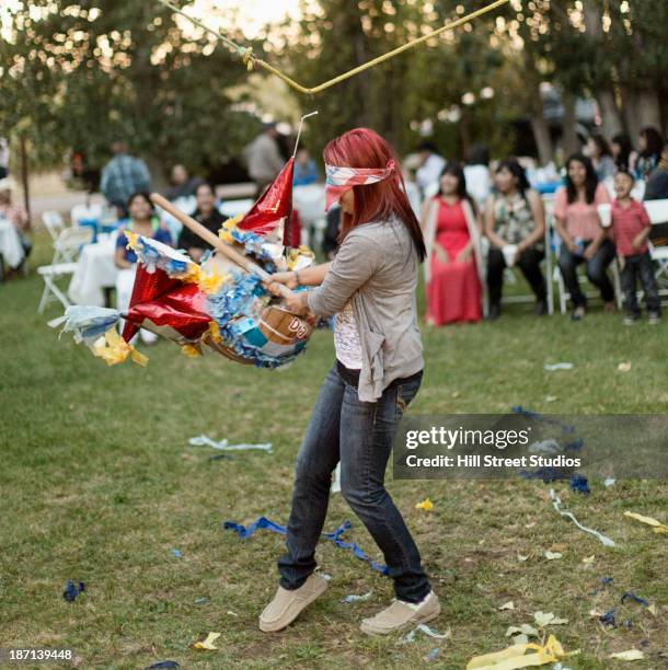 hispanic woman batting at pinata - pinata photos et images de collection