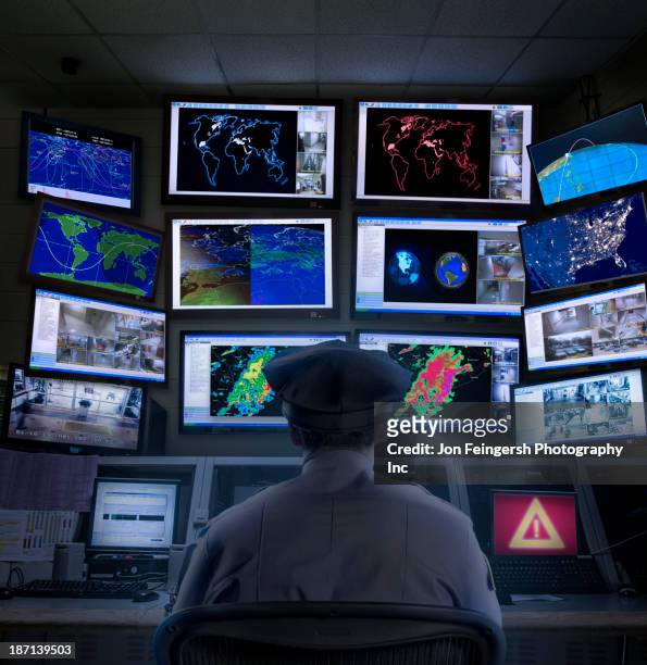 police officer working in control room - watching tv from behind stockfoto's en -beelden