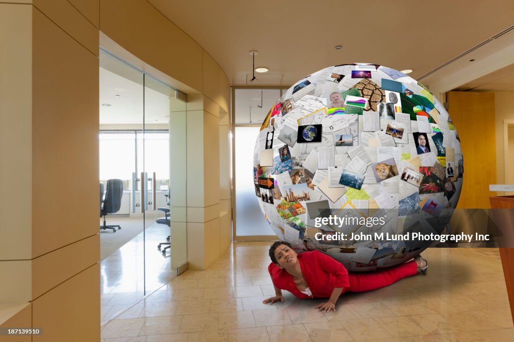 Businesswoman stuck underneath globe of images in office