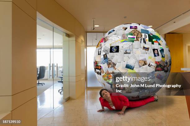 businesswoman stuck underneath globe of images in office - businesswoman under stock pictures, royalty-free photos & images