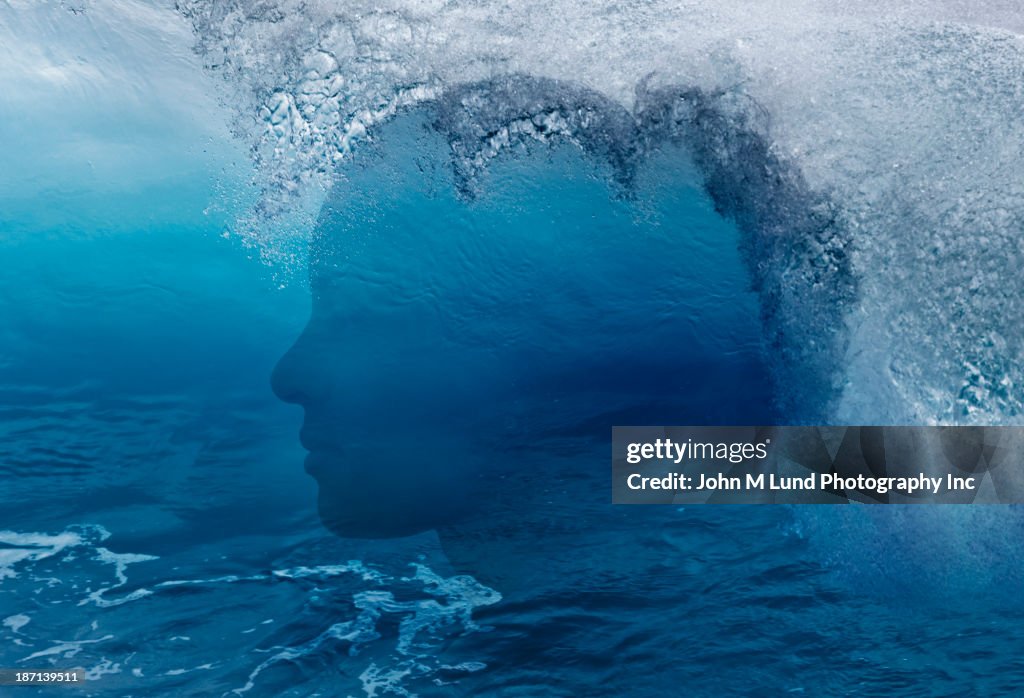 Mixed race woman's silhouette over ocean waves