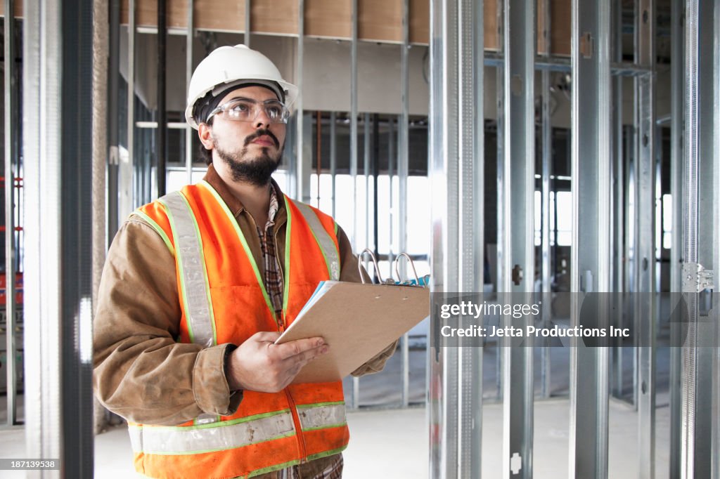 Hispanic construction worker writing on clipboard