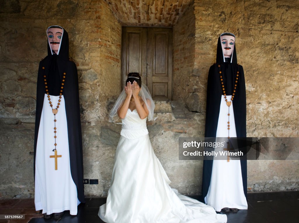 Bride standing between priest statues at church