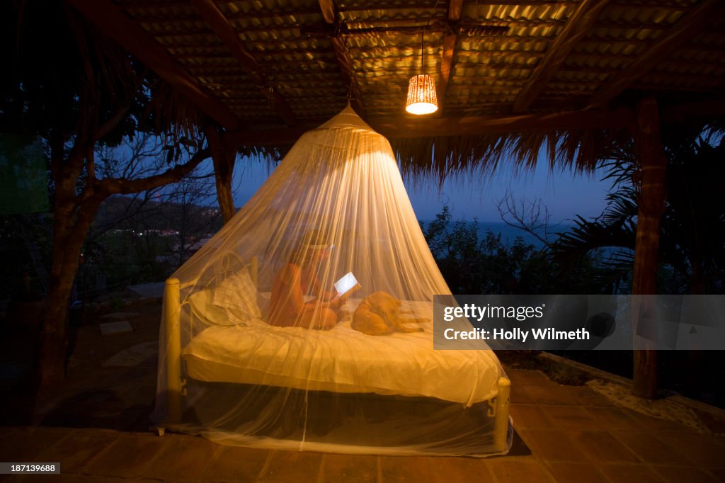 Caucasian woman using digital tablet under mosquito net
