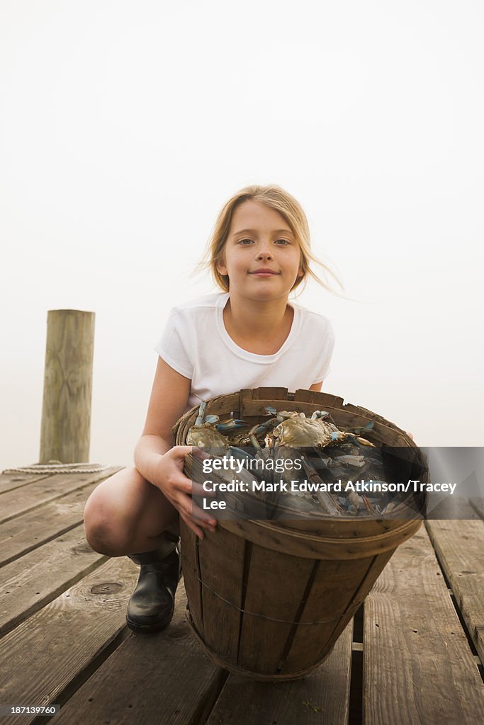 Caucasian girl holding basket of crabs