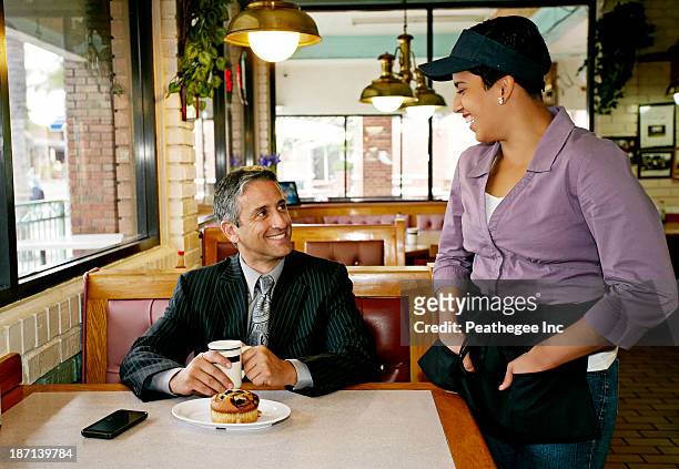 hispanic waitress talking to businessman in restaurant - waitress booth stock pictures, royalty-free photos & images