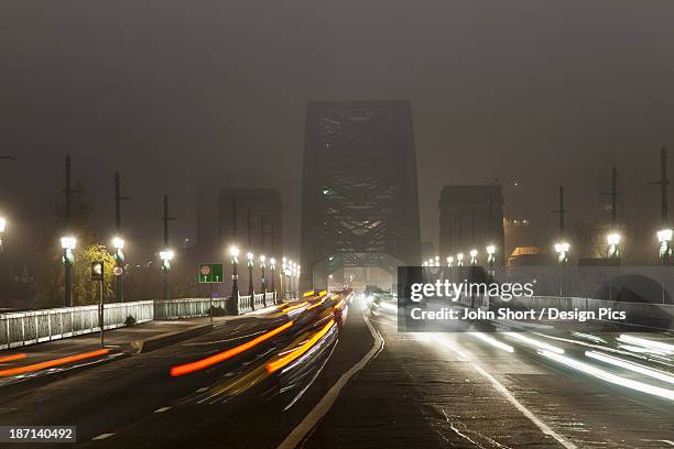 light trails of vehicle headlights and tail lights on a busy road leading to a bridge at night - tyne bildbanksfoton och bilder