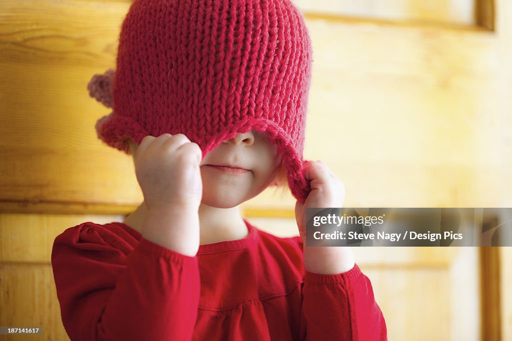 A Child Pulling A Hat Over Her Eyes