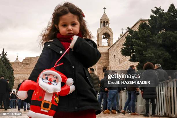 Girl stands with an inflatable Father Christmas doll at the Manger Square outside the Church of the Nativity in the biblical city of Bethlehem in the...