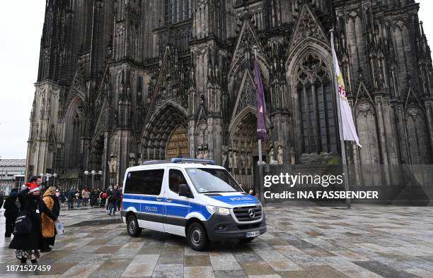 Police car drives in front of the Cologne Cathedral on December 24, 2023. German police announced on December 23, 2023 evening they were searching...