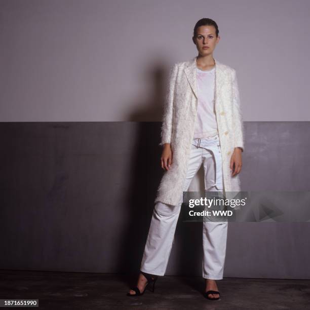 Model wearing a fuzzy white coat with t-shirt and white pants with knee-pads from the Helmut Lang Spring/Summer 1999 collection