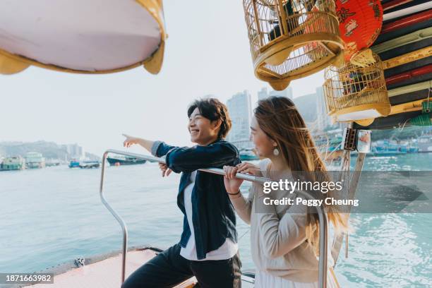 a chinese couple enjoying the breathtaking view from the sampan boat - hong kong chinese lanterns stock pictures, royalty-free photos & images