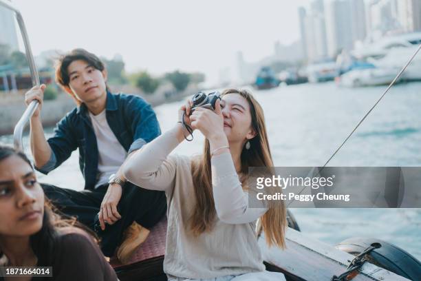 a chinese tourist taking a photo of the sky with a camera on a sampan boat in aberdeen harbour - camera boat stock pictures, royalty-free photos & images