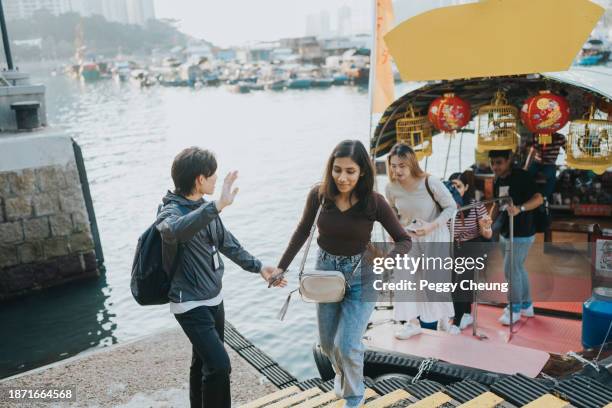 a chinese tour guide helping a group of tourists to get off a small board at the aberdeen's fishing port - indian tour guide stock pictures, royalty-free photos & images
