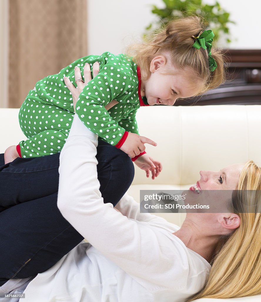 Madre tenendo la figlia bambino e ridere a Natale