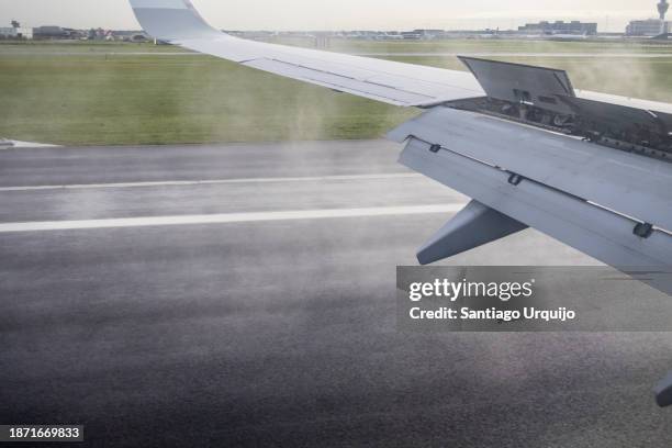 airplane wing flaps up while landing at amsterdam airport - flapping wings stock pictures, royalty-free photos & images