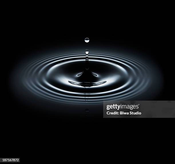 water drop making ripple on black background - water ripple stock-fotos und bilder