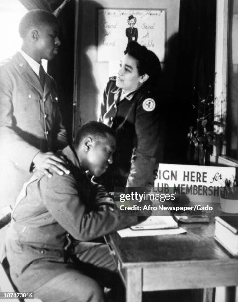 Private Robert Nickerson signs his Red Cross club application while Henrine E Ward and Pfc Sherman Powell look on, Bristol, Tennessee, 1945.