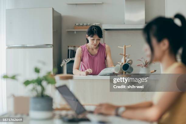 a woman is at home, holding a collection of paper bills and financial plans. she appears to be focused on managing her personal finances, possibly sorting through bills, budgeting, or organizing her financial matters. - matters stock pictures, royalty-free photos & images