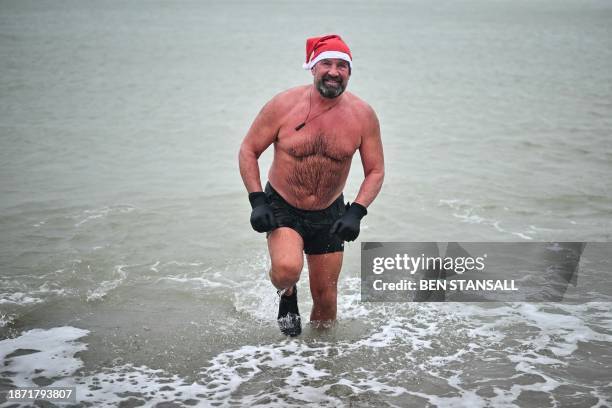 Man wearing a Santa Claus hat comes out of the sea after a swim, near the port of Dover, south England on December 24 on the eve of Christmas day.