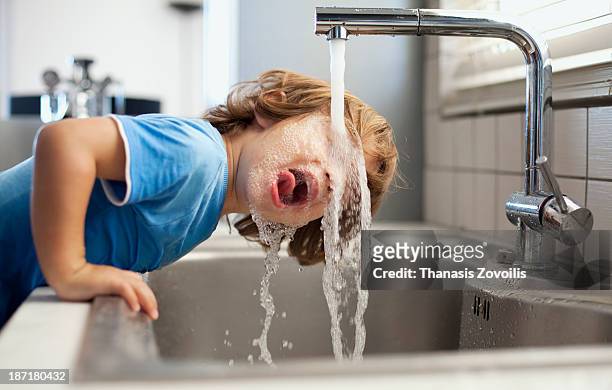 small boy drinking water - faucet stock-fotos und bilder