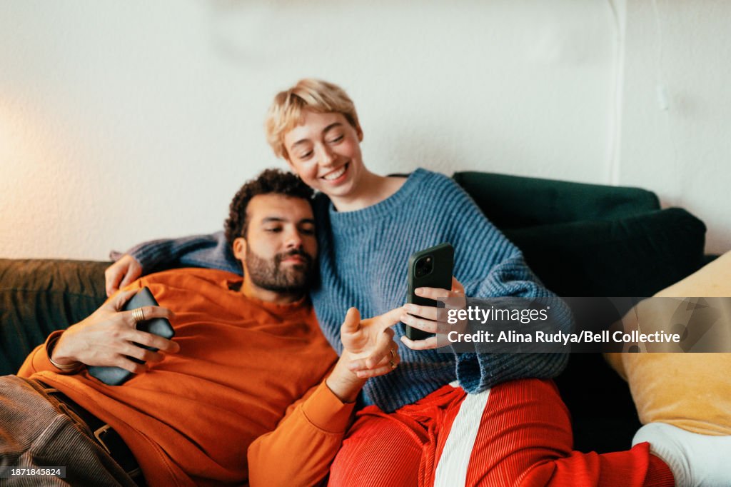 Young couple chilling on a couch with smartphone