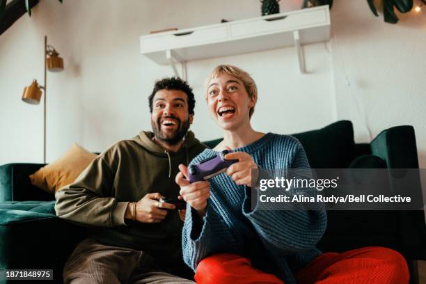 young couple playing video games on a console - brand name video game imagens e fotografias de stock