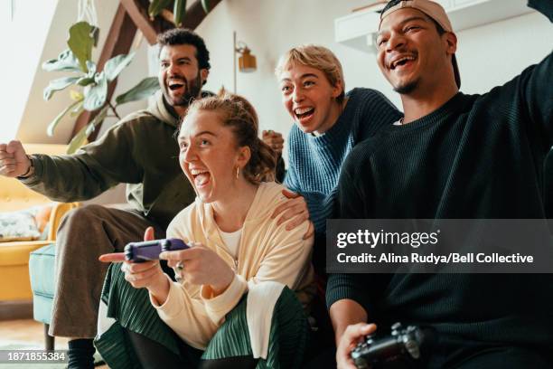 group of friends playing video games on a console - videospel stockfoto's en -beelden