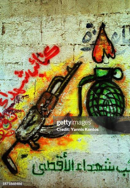 Palestinian graffiti depicts an AK-47 machine gun and a hand grenade on a wall in the Beach refugee camp in Gaza on December 14, 2001.