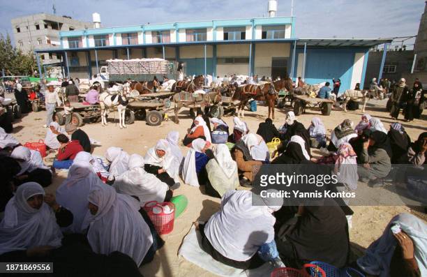 Palestinian refugees wait for humanitarian aid at the UNRWA distribution center in the Khan Younis refugee camp on December 16, 2001.