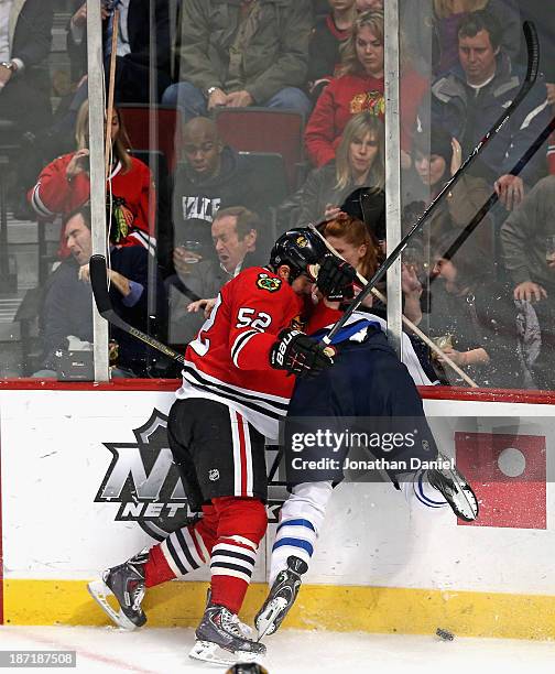 Brandon Bollig of the Chicago Blackhawks checks Adam Pardy of the Winnipeg Jets through the glass at the United Center on November 6, 2013 in...