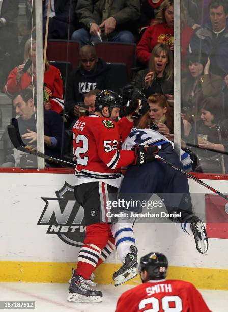 Brandon Bollig of the Chicago Blackhawks checks Adam Pardy of the Winnipeg Jets through the glass at the United Center on November 6, 2013 in...