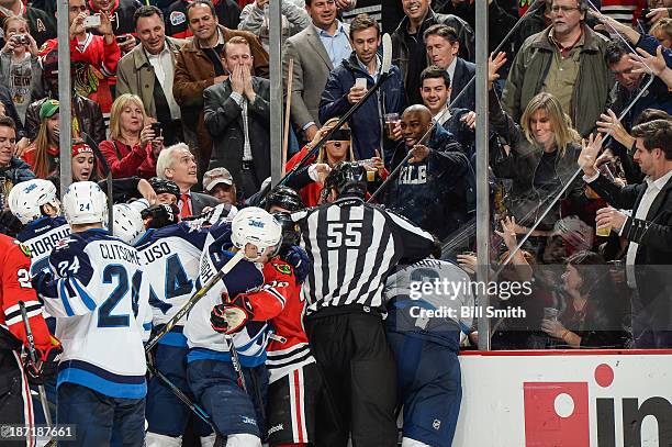 Linesman Shane Heyer attempts to break up the fight between the Jets and the Blackhawks after the glass gave way from a hard check to Adam Pardy of...