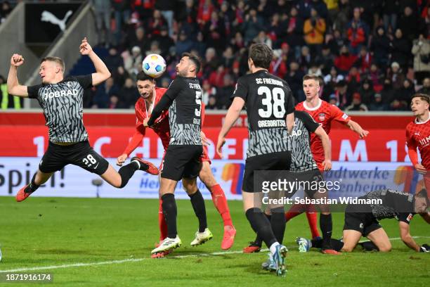 Matthias Ginter and Manuel Gulde of SC Freiburg compete with Tim Kleindienst of 1. FC Heidenheim 1846 for the ball during the Bundesliga match...