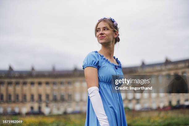 jovem usando um vestido da era regência está andando em um parque público em frente ao royal crescent - estilo regency - fotografias e filmes do acervo