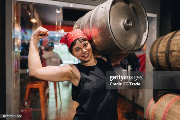 portrait of a mid adult woman carrying barrel of beer on a microbrewery - entrepreneur stockfoto's en -beelden