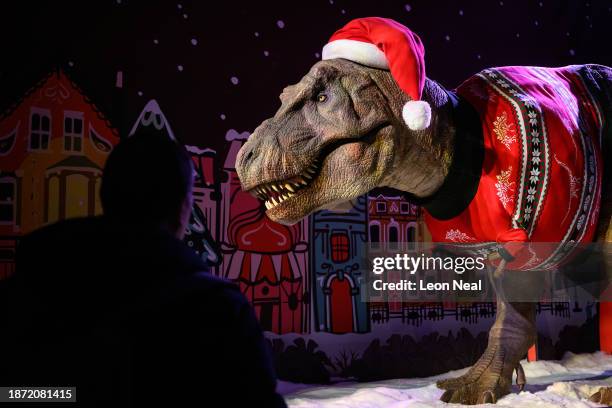 Visitors stop to look at an animated model of a Tyrannosaurus Rex wearing a Santa hat and festive jumper in it's Christmas-themed display at the...