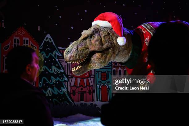 Visitors stop to look at an animated model of a Tyrannosaurus Rex wearing a Santa hat and festive jumper in it's Christmas-themed display at the...