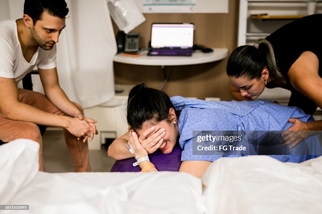 Doula helping pregnant women during birth at hospital