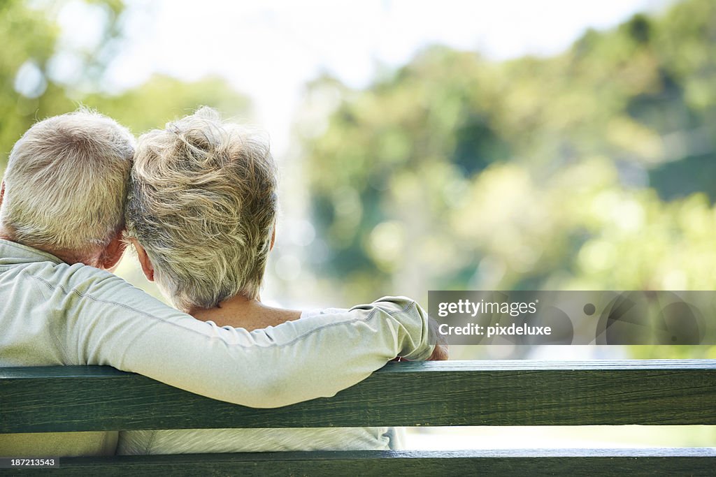 Elderly man and woman embracing on outdoor bench