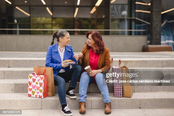 mature women lesbian couple shopping resting stairs, black friday shopping, valentine's day - valentin martinez foto e immagini stock