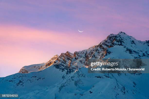 pink sky at sunset over snowy mountain peaks - montagne photos et images de collection