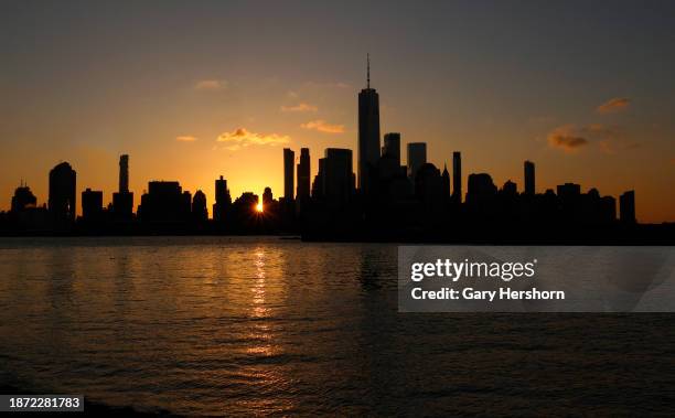 The sun rises behind the skyline of lower Manhattan and One World Trade Center on the winter solstice in New York City on December 21 as seen from...