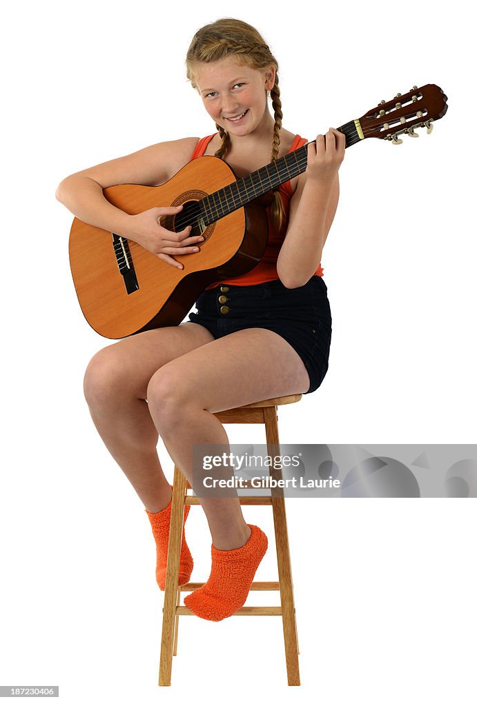 Teenage girl sitting on a stool with guitar
