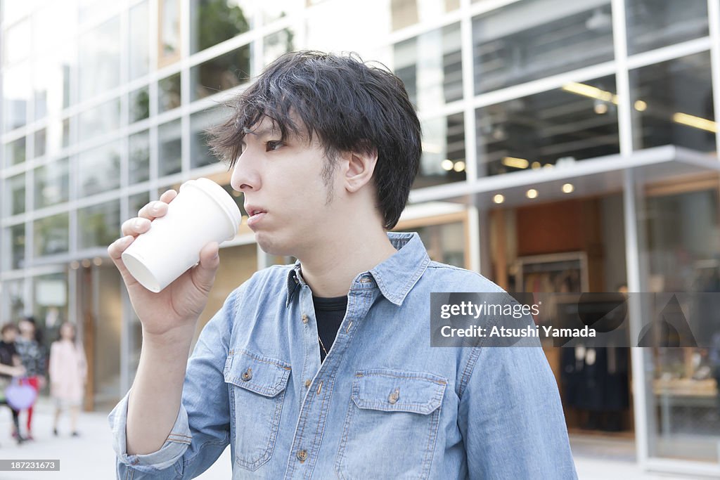 Young man having coffee on street