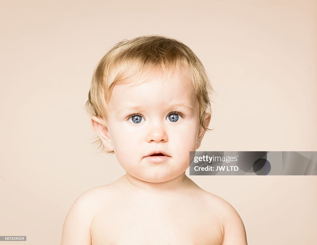 Blue eyed baby girl looking to camera, studio