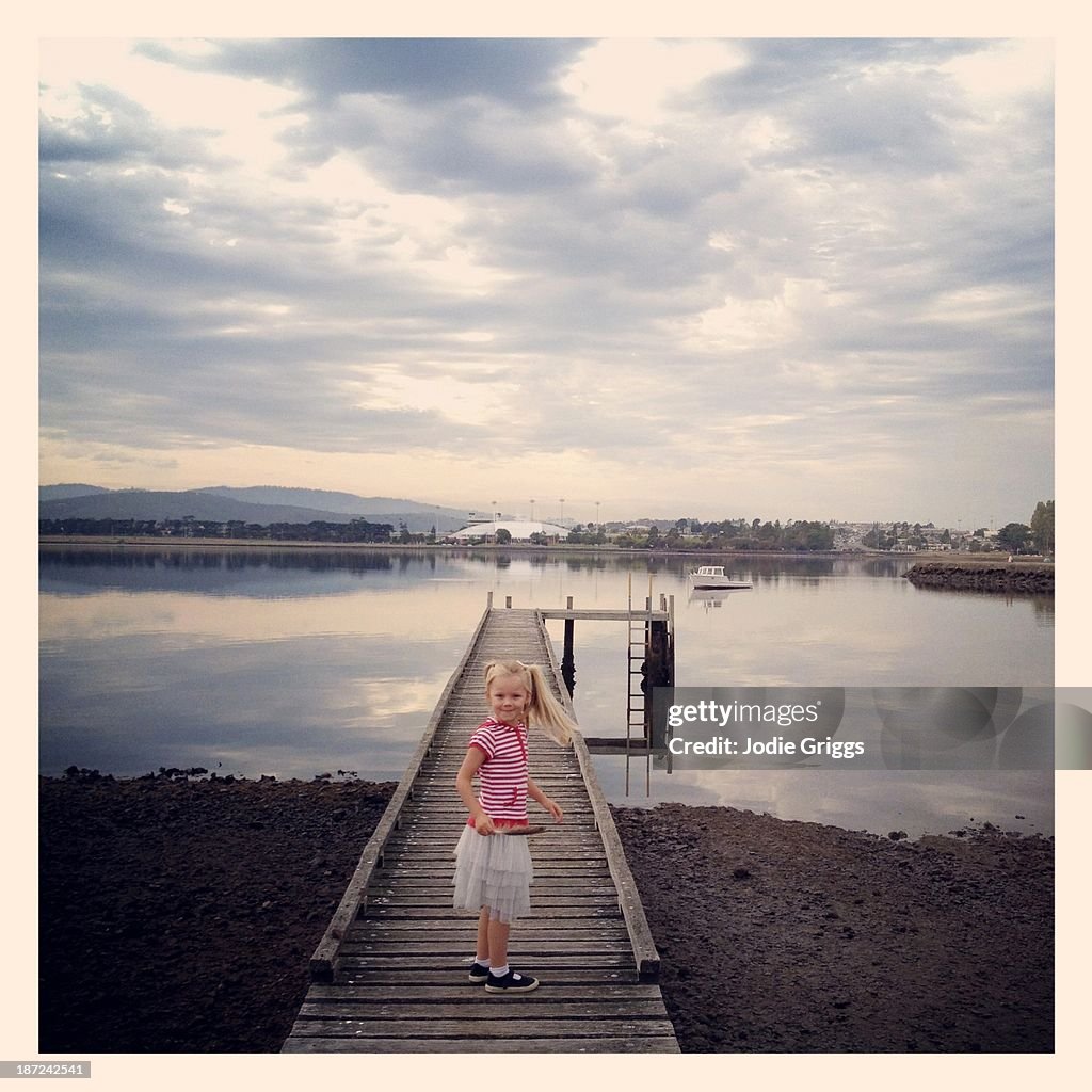 Child standing on wooden jetty by the river