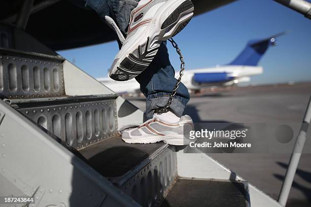 Honduran immigration detainee, his feet shackled and shoes laceless as a security precaution, boards a deportation flight to San Pedro Sula, Honduras...