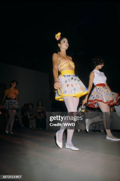 Model wearing halter bikini top with flirty mini skirt decorated with multi-colored confetti triangles from the runway of Gaultier's 1979 ready to...