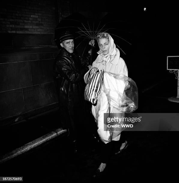 Female guest arriving under an umbrella at author Truman Capote's Black and White masquerade ball